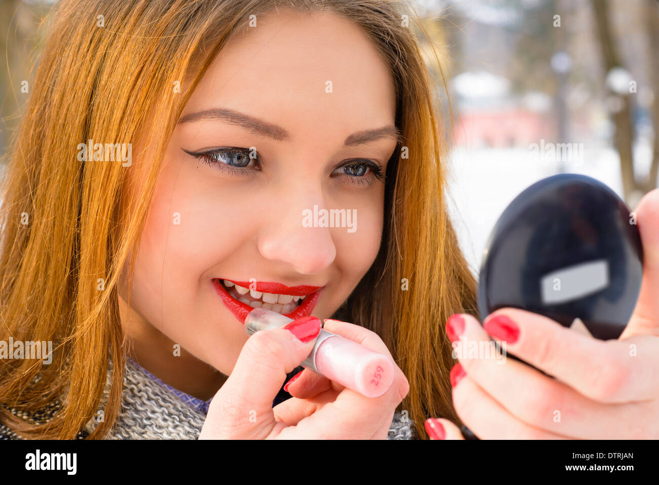 Beautiful young woman applying lipstick Stock Photo