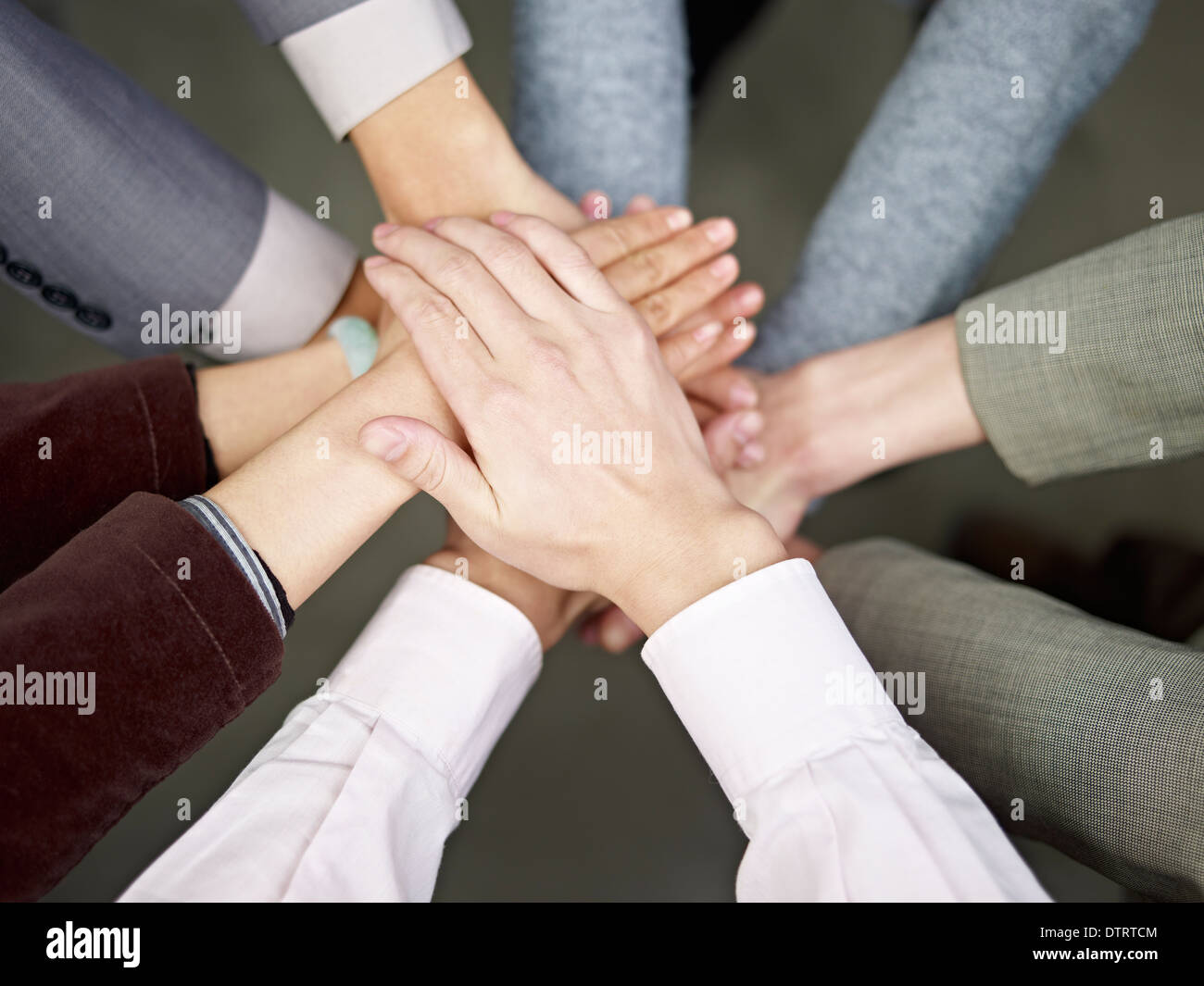team of businesspeople showing unity by putting hands together. Stock Photo