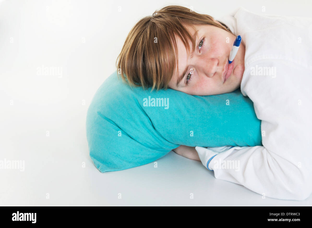 Sick girl with head on pillow and thermometer in her mouth. Stock Photo