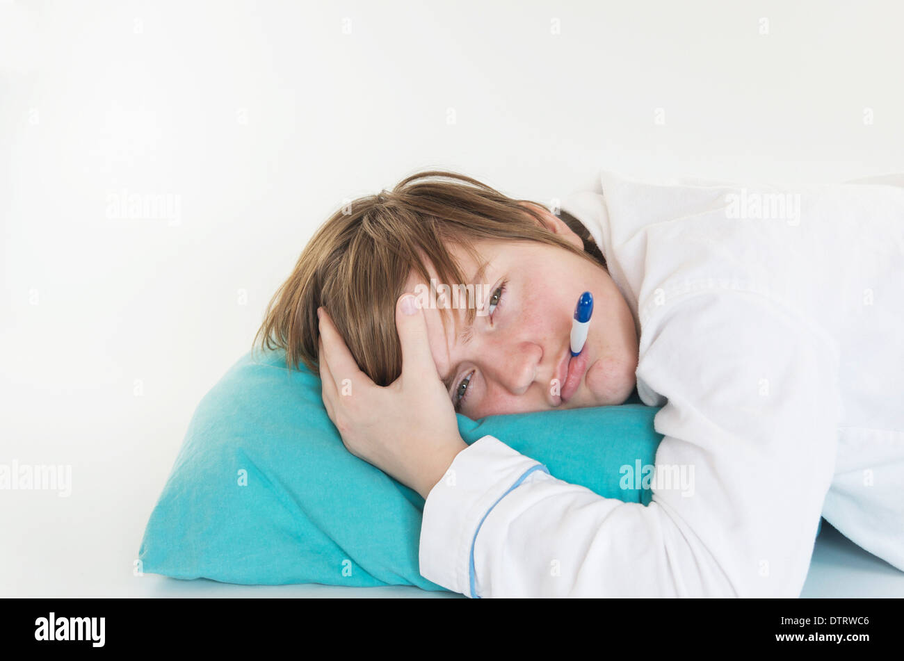 Sick girl with thermometer in her mouth laying on a pillow. Stock Photo