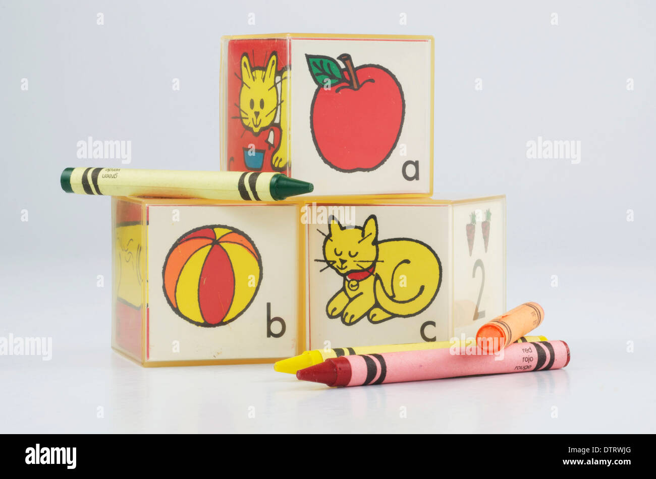 Educational Plastic preschool blocks with ABC's and picture of an apple,ball, and cat. Crayons of red green,yellow,and orange. Stock Photo