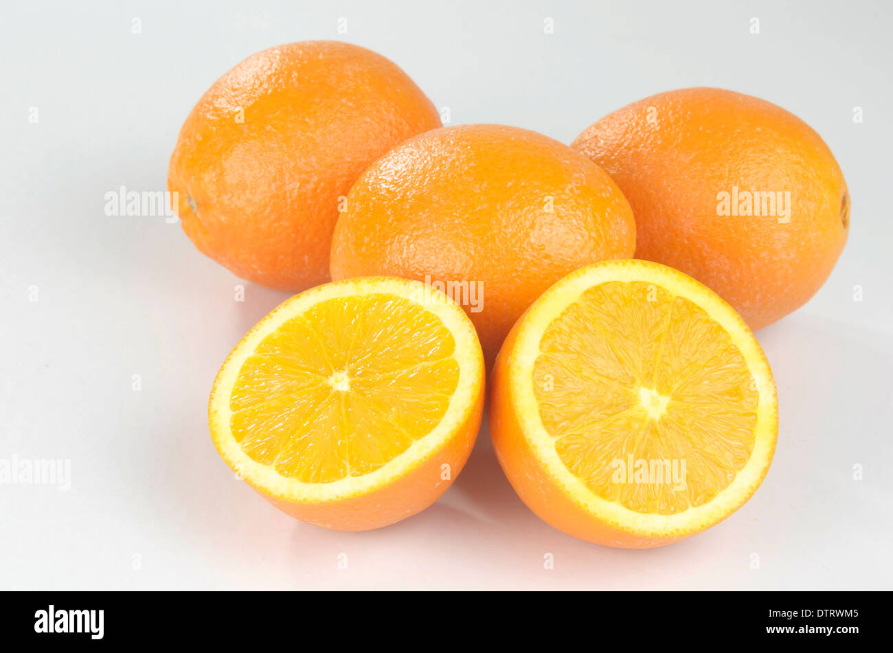 Whole oranges, with one cut open on white background. Stock Photo