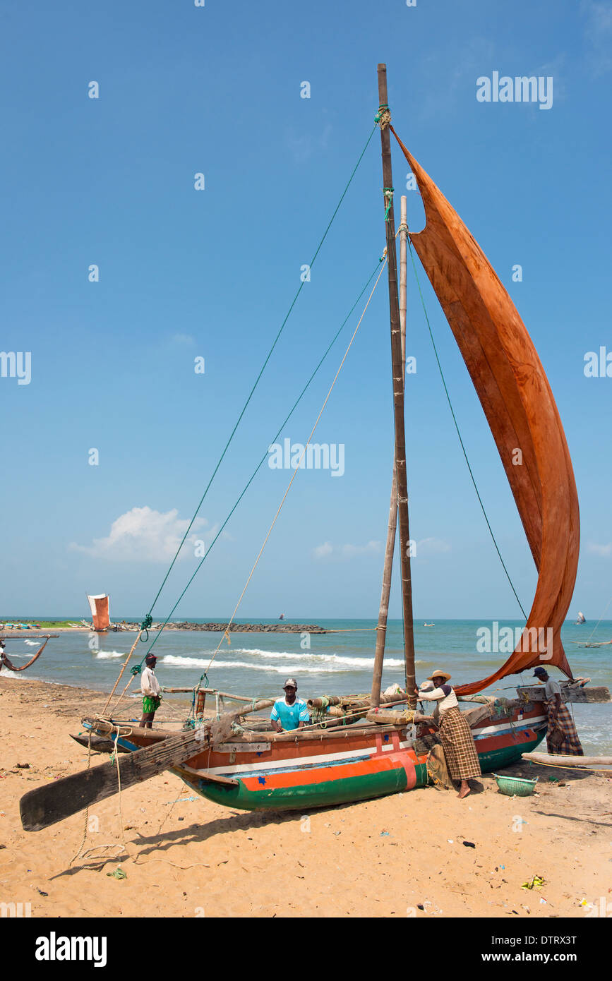 Fisherman with traditional outrigger sailing canoe known as Oruvas on the Negombo beach. Western Province, Sri Lanka. Stock Photo