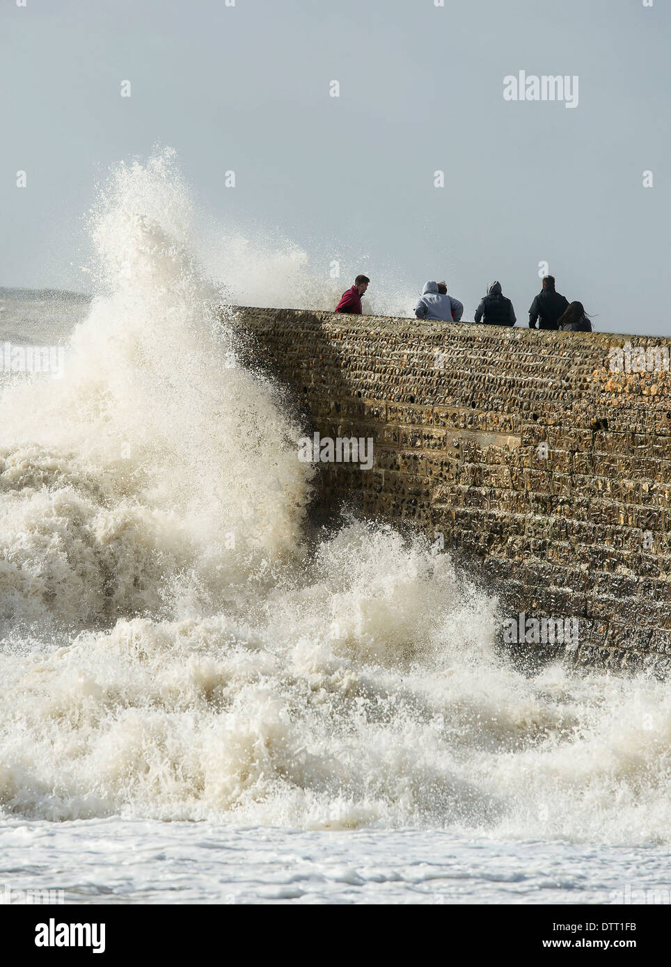 Thrill seekers run from huge waves during tidal surges on British coastlines in extreme weather. Scene in Brighton, Sussex, UK Stock Photo