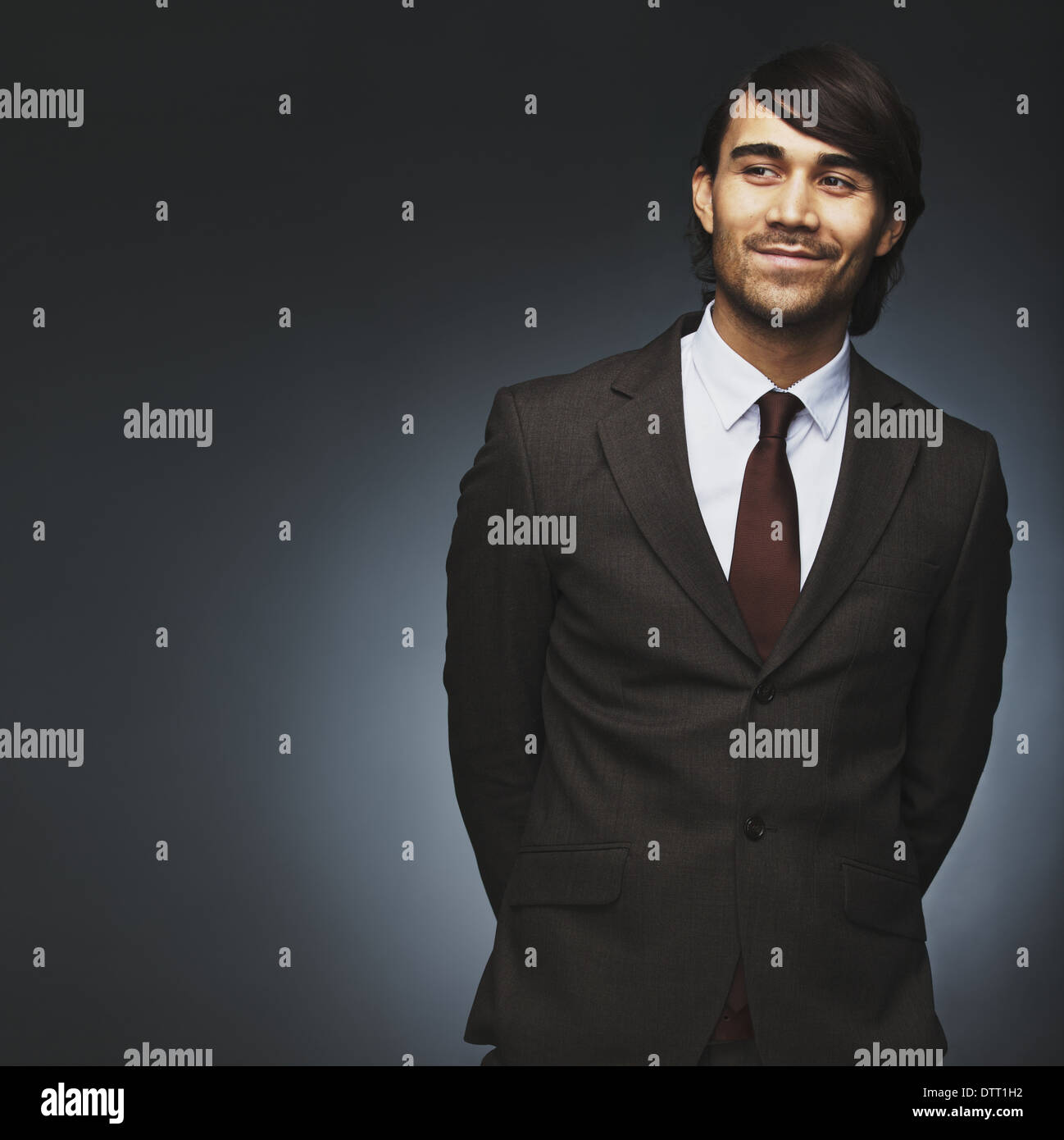 Handsome young man looking away smiling on black background. Male model in business suit looking at copyspace. Stock Photo