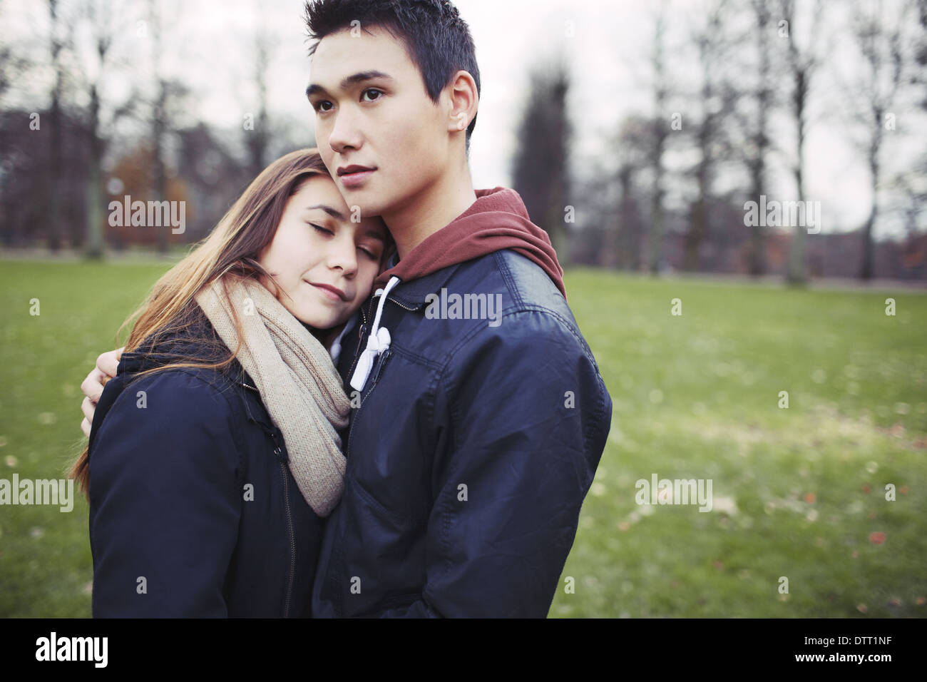 Affectionate teenage couple embracing outdoors. Young man and woman in love in park. Copyspace. Stock Photo