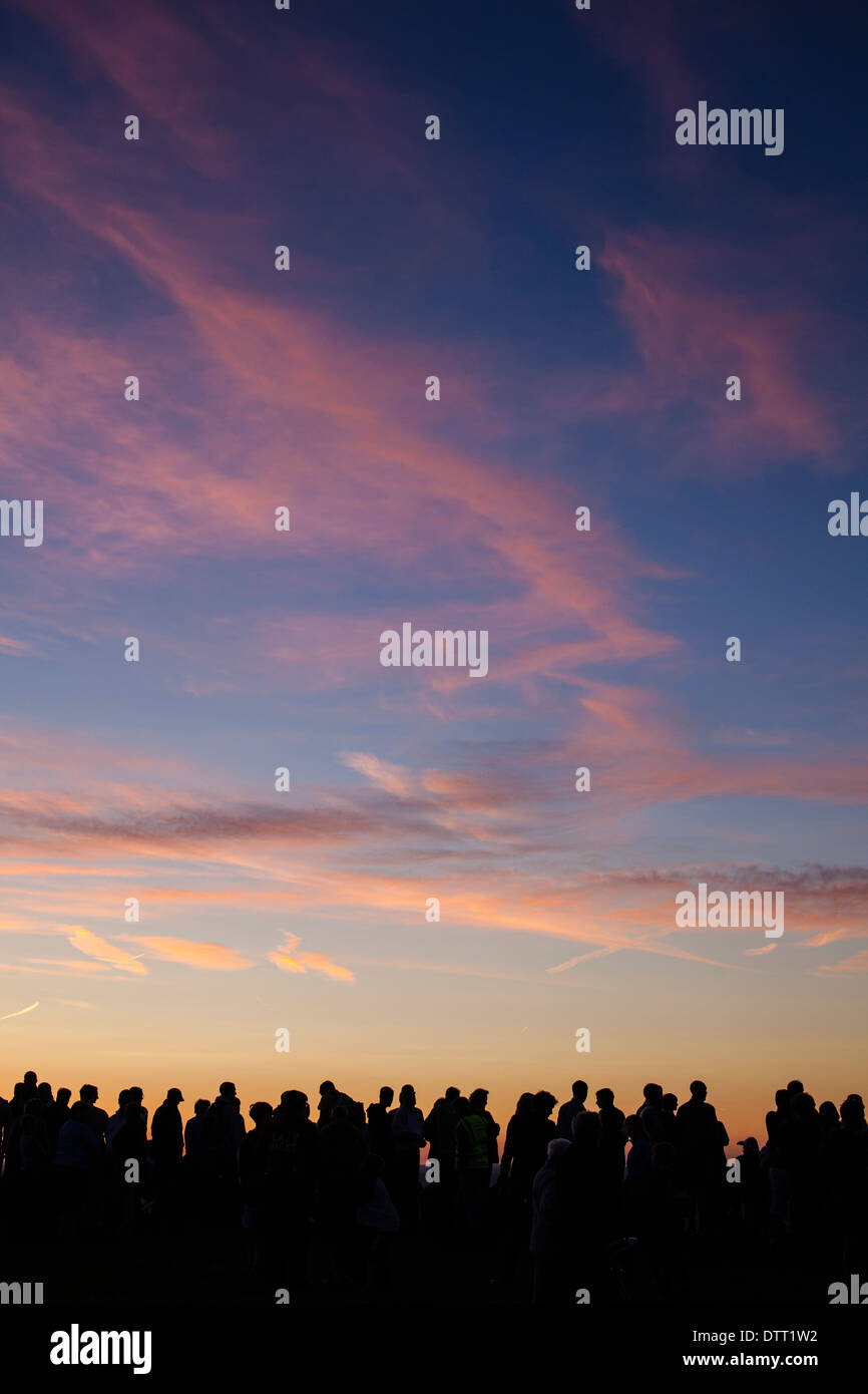 A large crowd of people against a sunset sky. Stock Photo