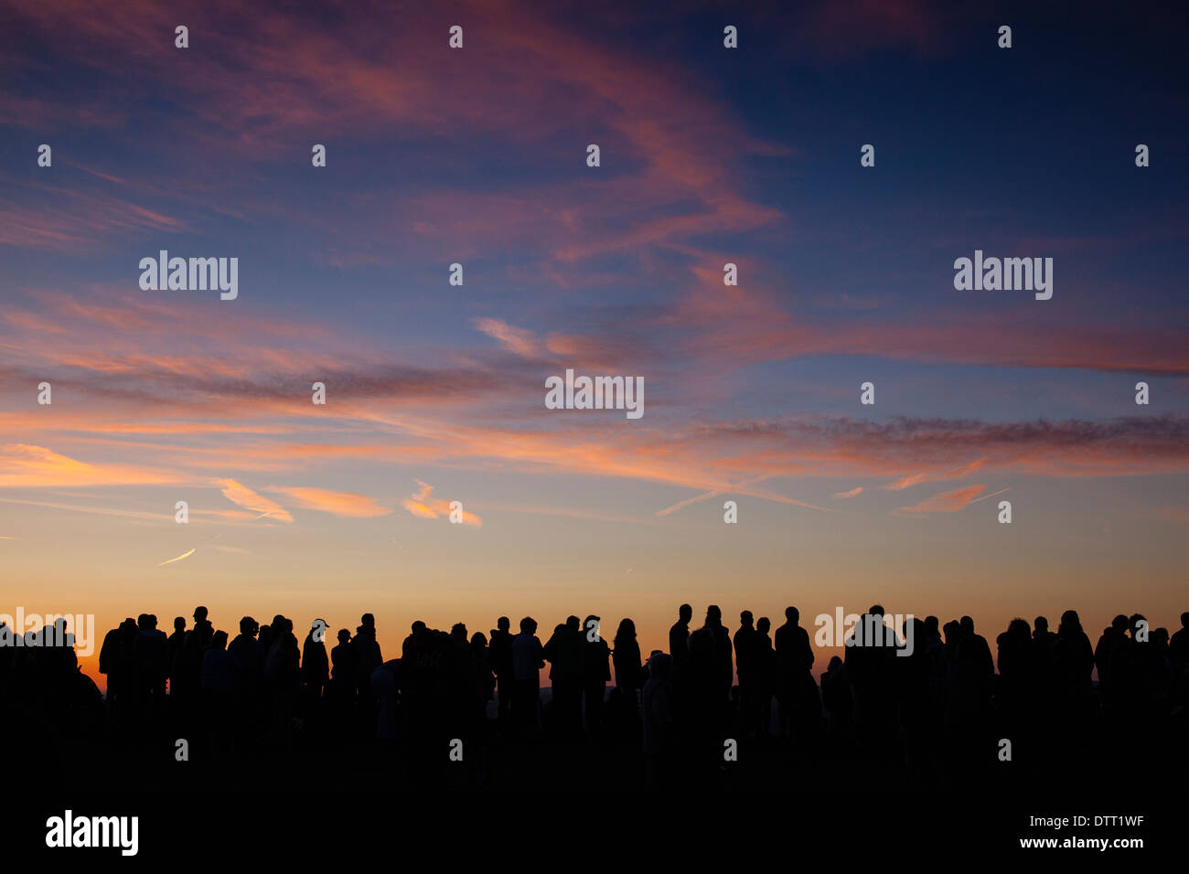 A large crowd of people against a sunset sky. Stock Photo