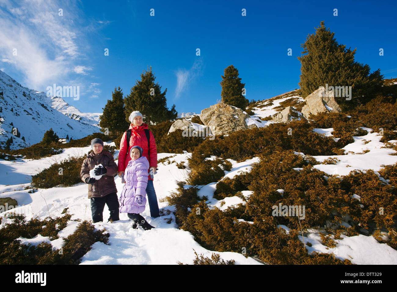 Family (mother with two children) take a walk on winter mountain slope (Big Almaty Lake, Kazakhstan) Stock Photo
