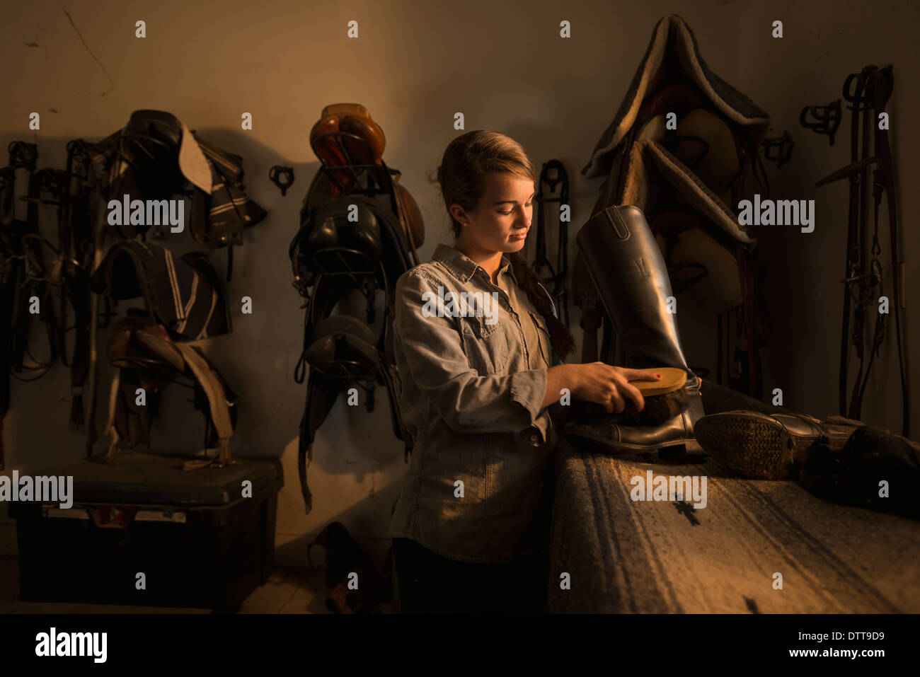 Caucasian girl caring for boots in horse stable Stock Photo Alamy