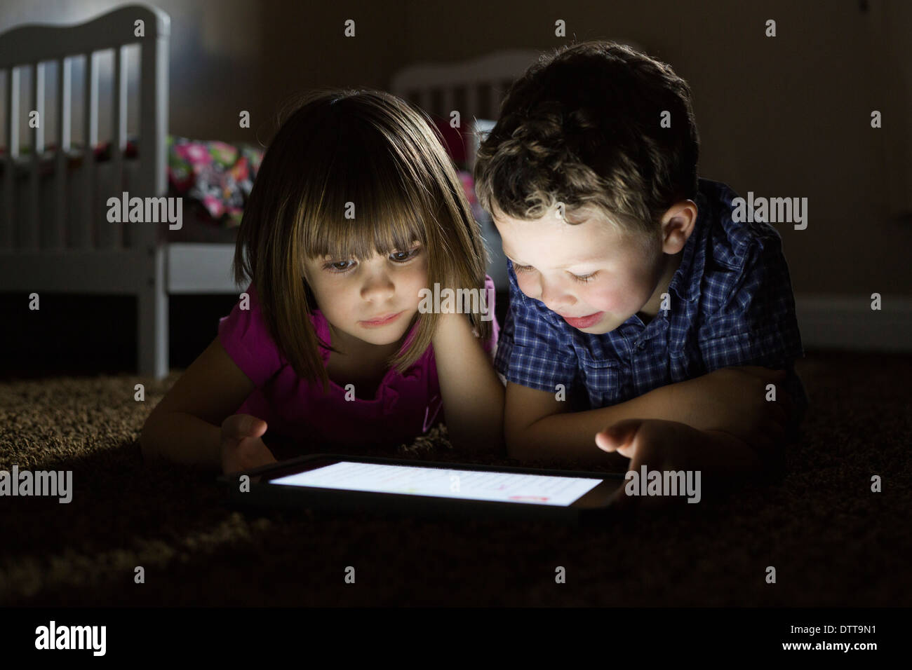 Caucasian children using digital tablet at night Stock Photo Alamy