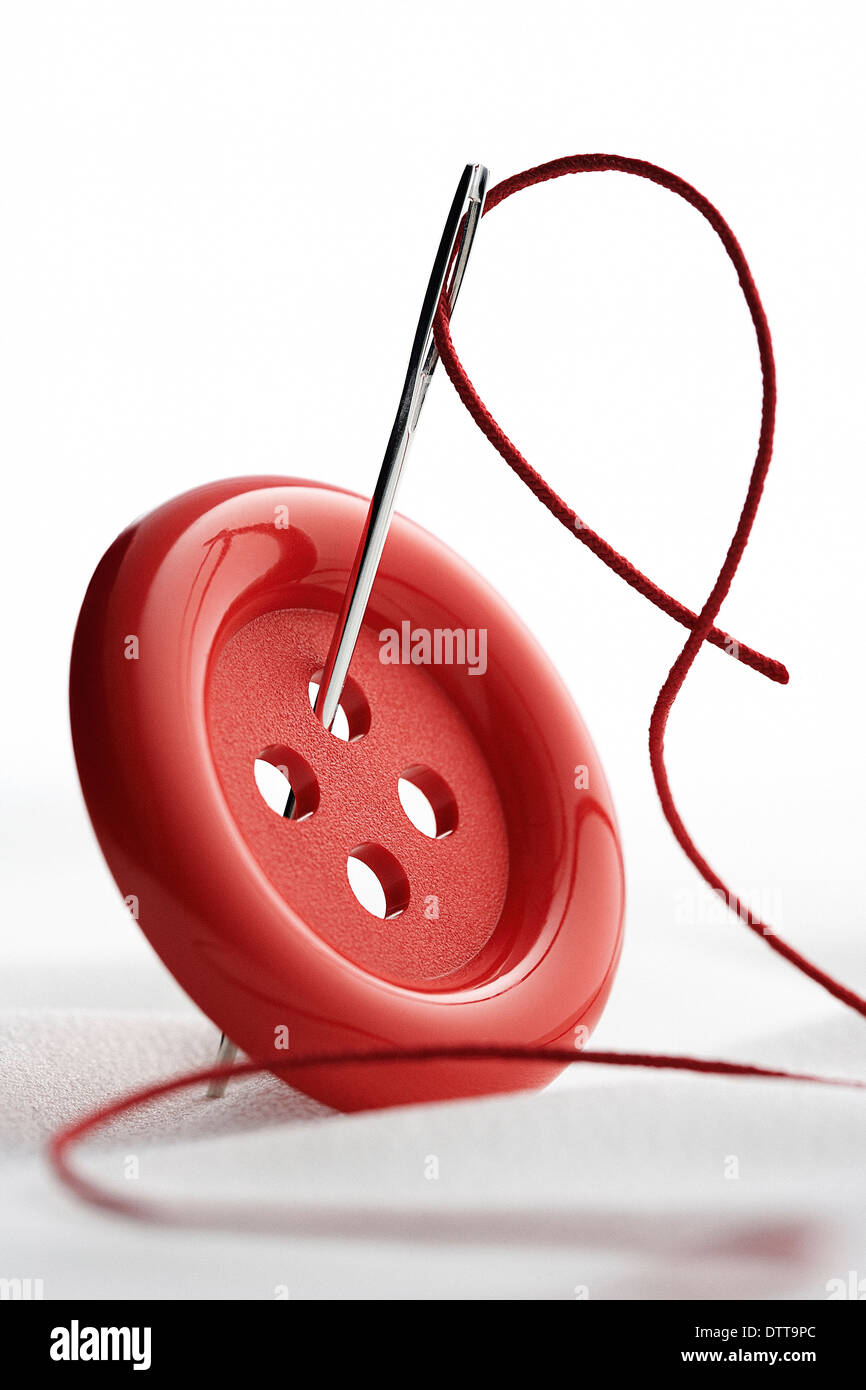 Close up of needle and thread through button Stock Photo Alamy