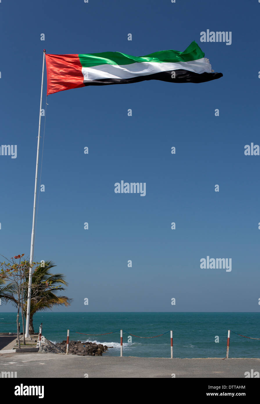 A UAE flag blowing in the window with the Arabian Gulf in the background.This was taken in Ras Al Khaimah in the UAE Stock Photo