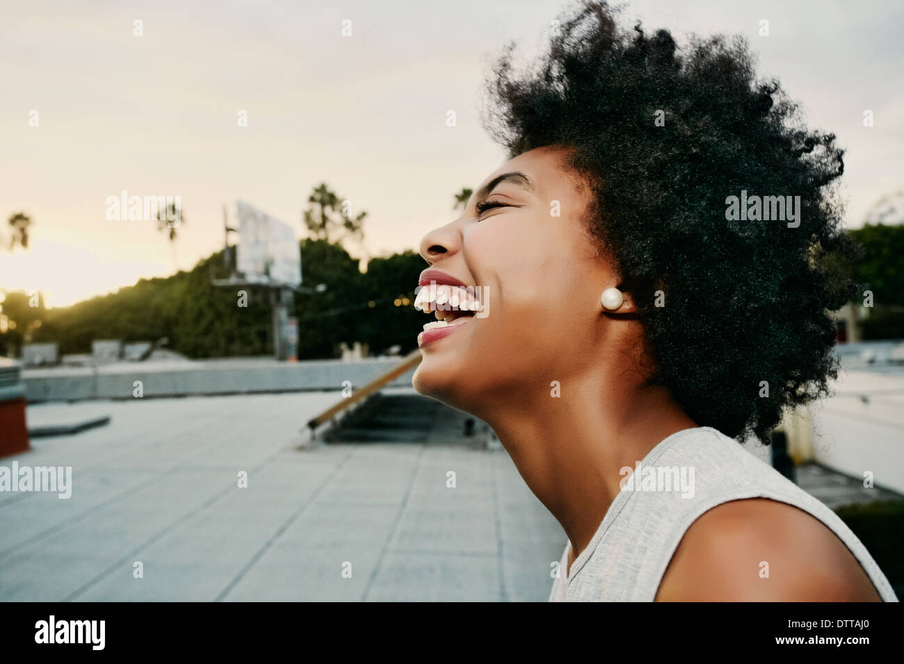 Mixed race woman laughing on urban rooftop Stock Photo