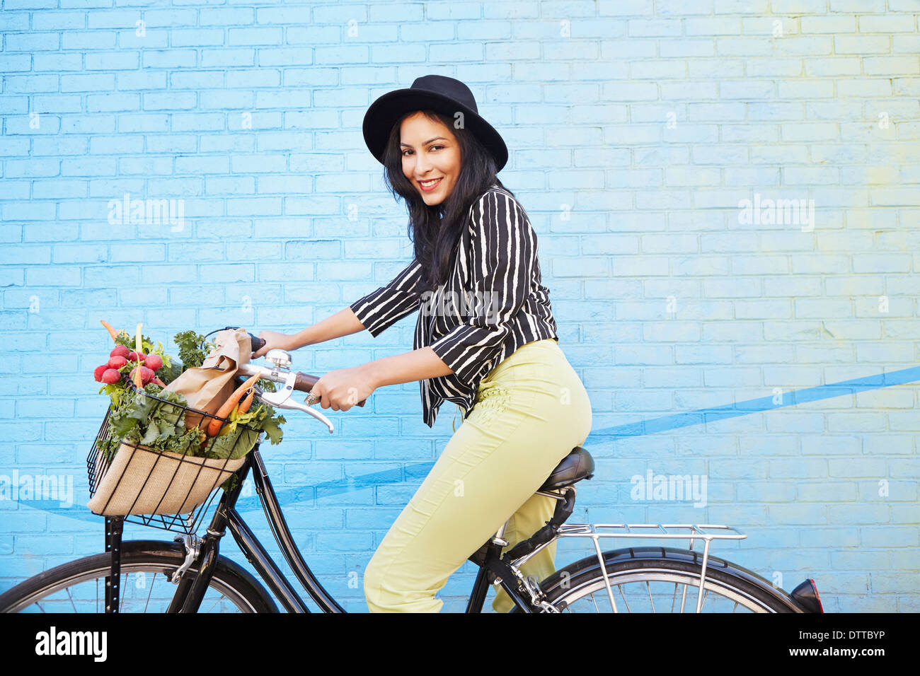 Indian woman riding bicycle along brick wall Stock Photo