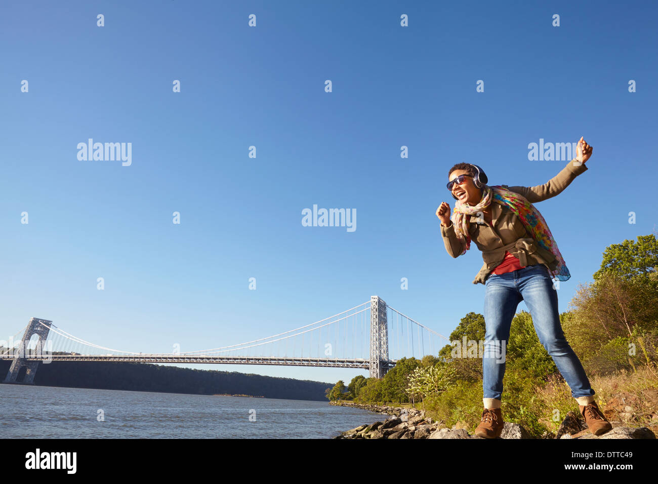Black woman listening to headphones at river Stock Photo