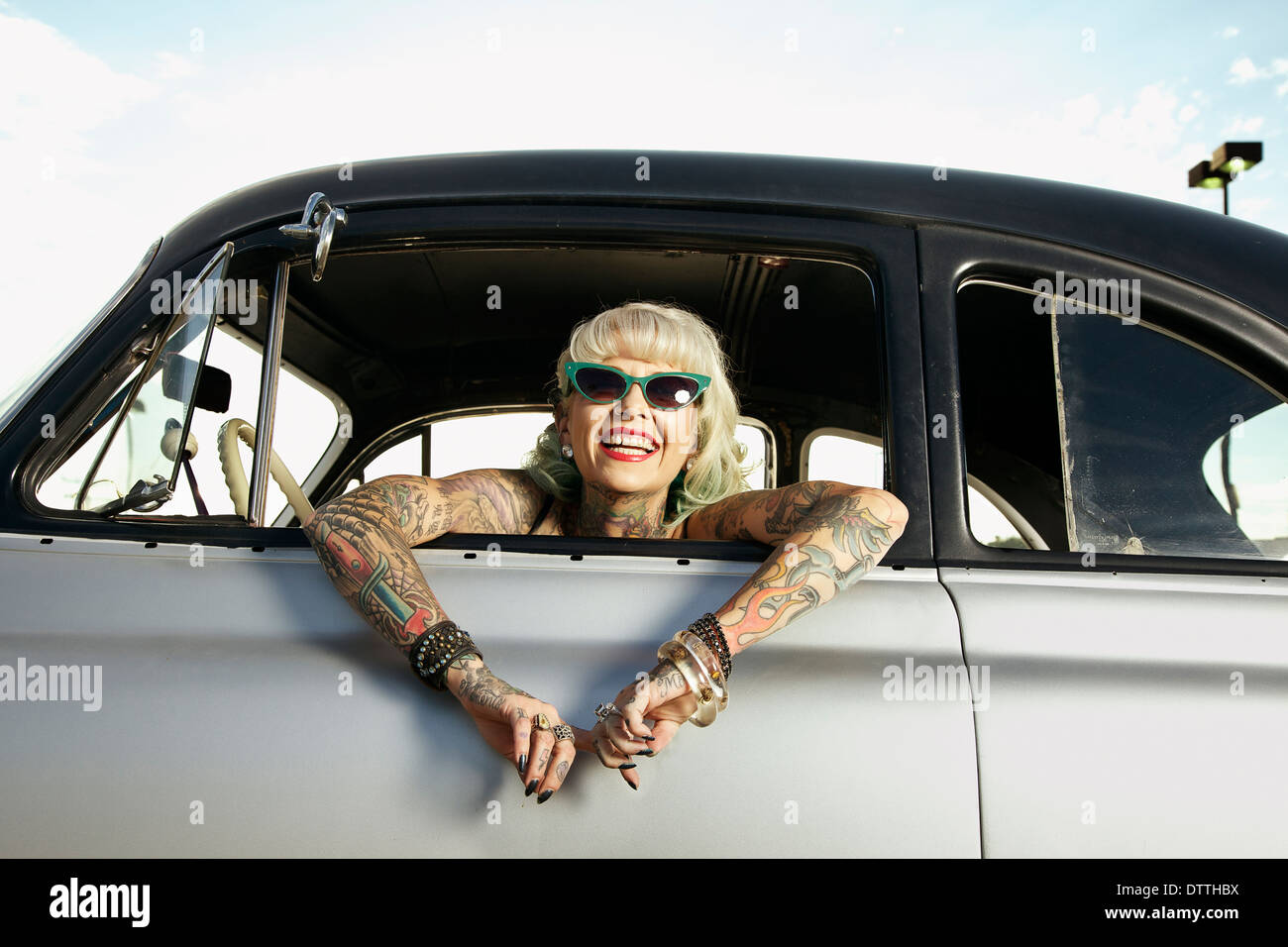 Woman with tattoos leaning out window of 1951 Chevy Stock Photo