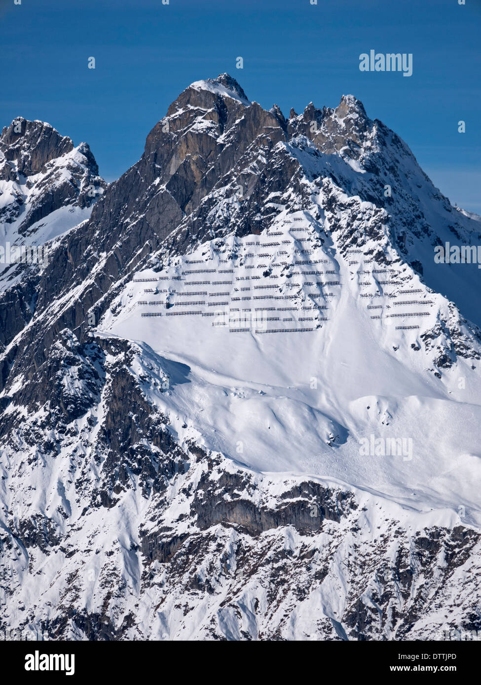 Avalanche barriers on a mountain peak near St Anton in Austria. Ski tracks can be seen where skiers have traversed across R to L Stock Photo