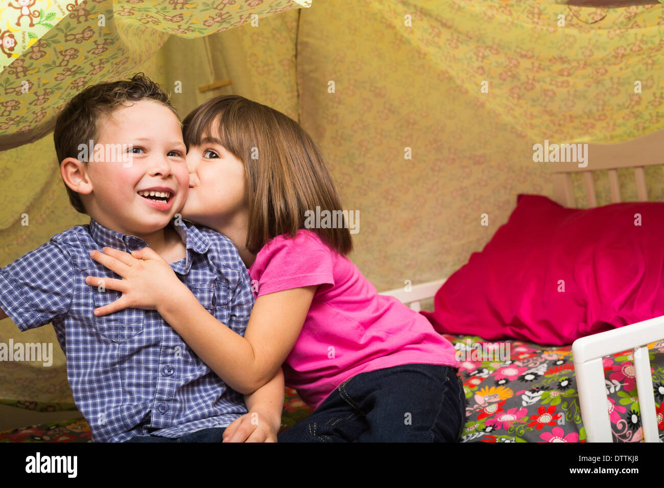 Caucasian children kissing in blanket fort Stock Photo