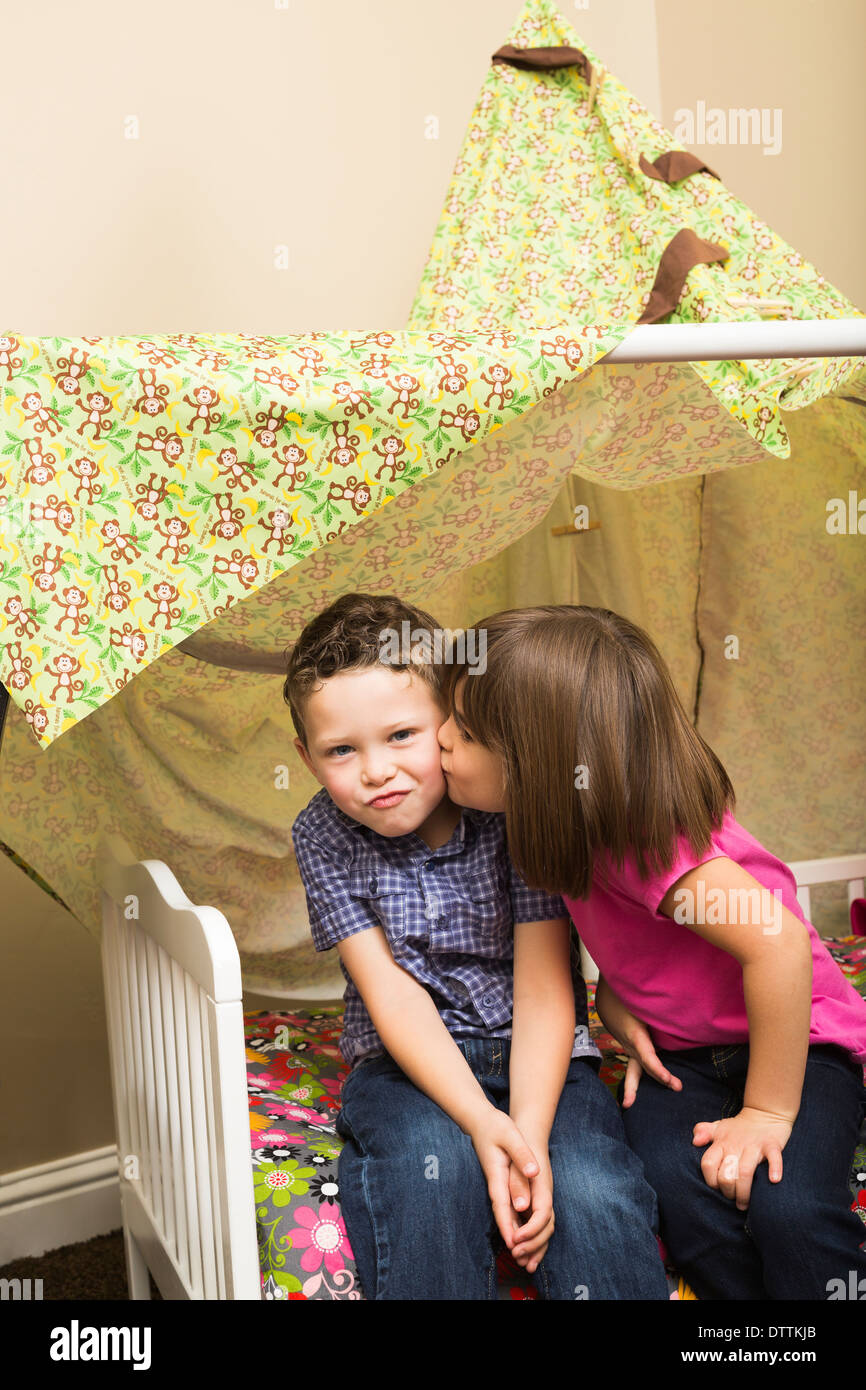 Caucasian children kissing in blanket fort Stock Photo
