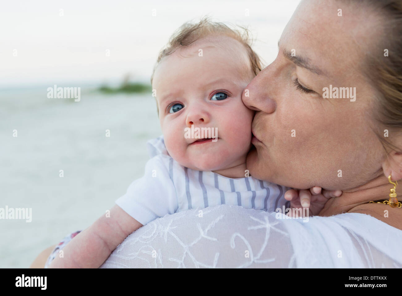 Mother kissing baby on beach Stock Photo Alamy