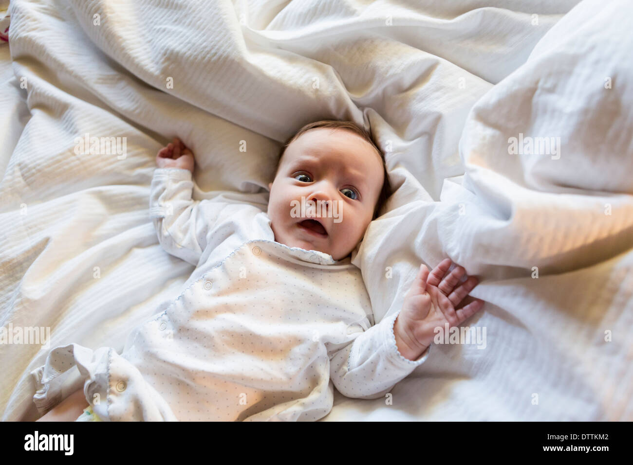 Caucasian baby gasping in bed Stock Photo