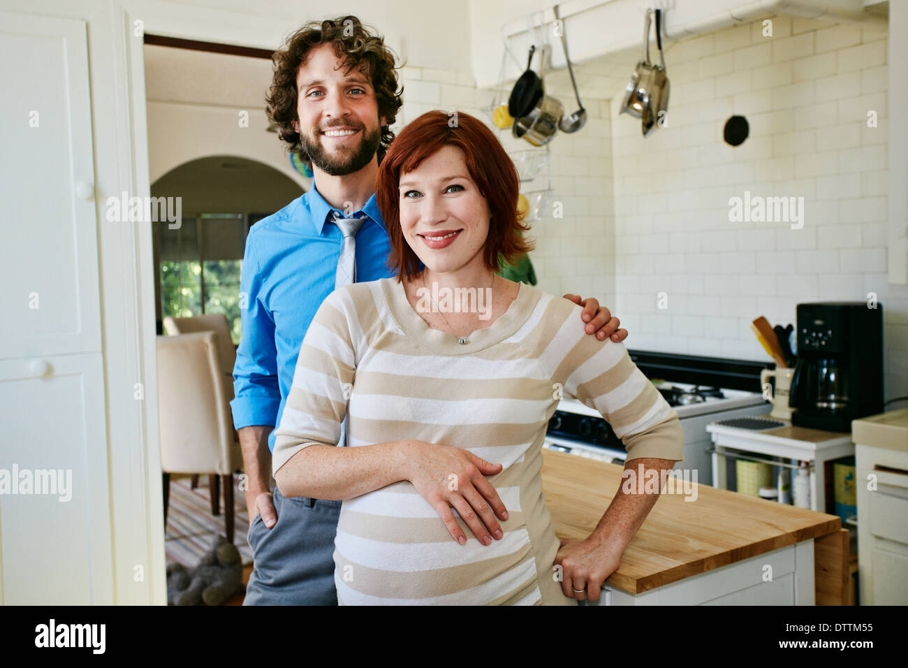 Pregnant Caucasian couple smiling in kitchen Stock Photo