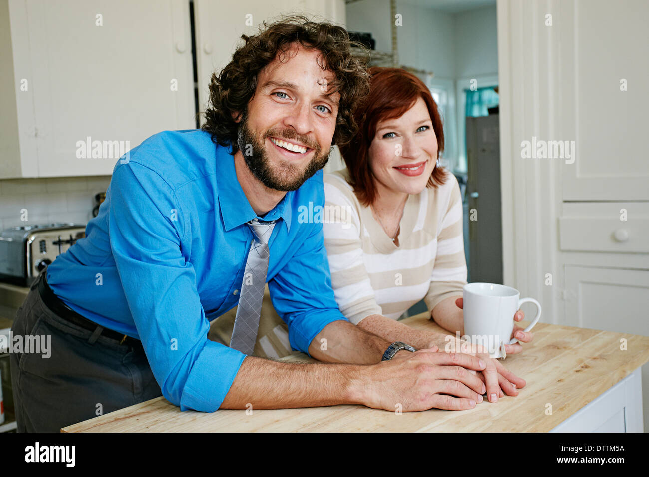 Pregnant Caucasian couple smiling in kitchen Stock Photo