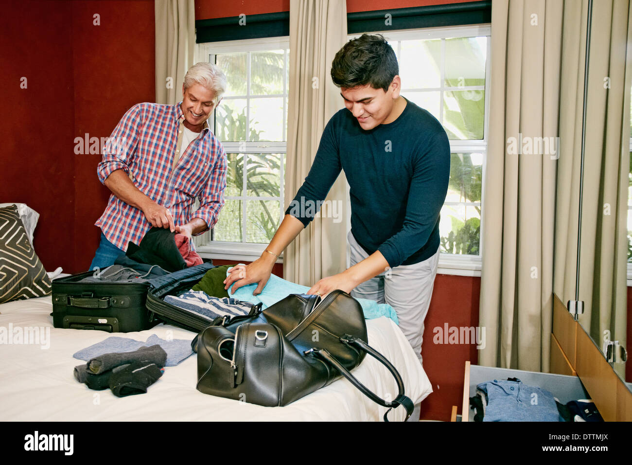Homosexual couple packing suitcases in bedroom Stock Photo