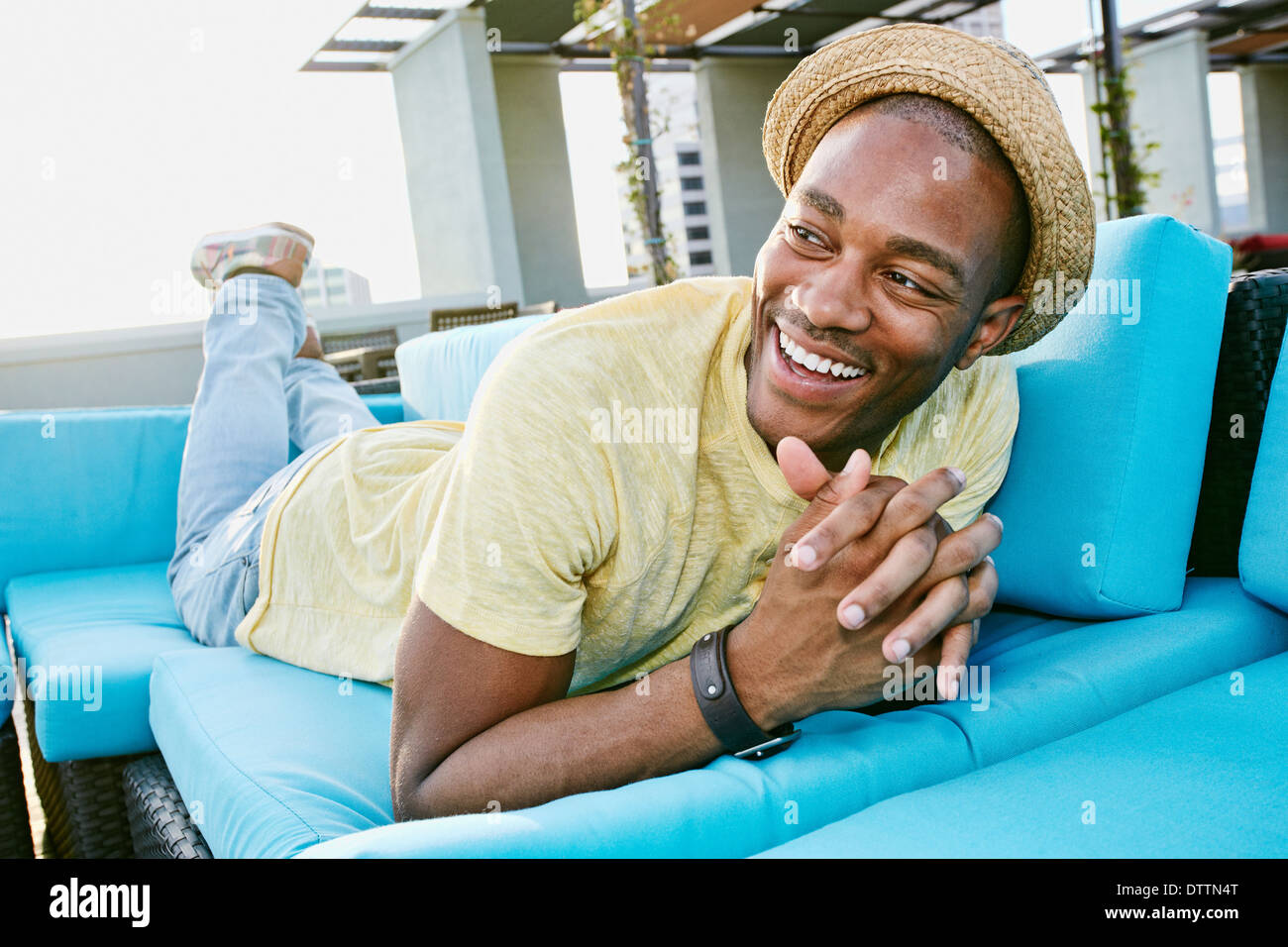 Black man relaxing on sofa on urban rooftop Stock Photo