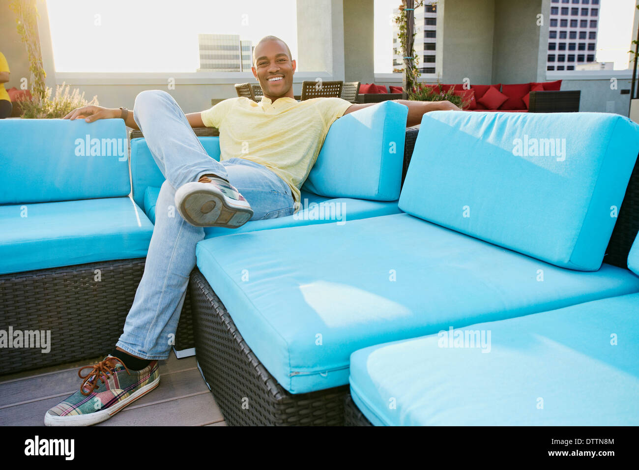 Black man relaxing on sofa on urban balcony Stock Photo