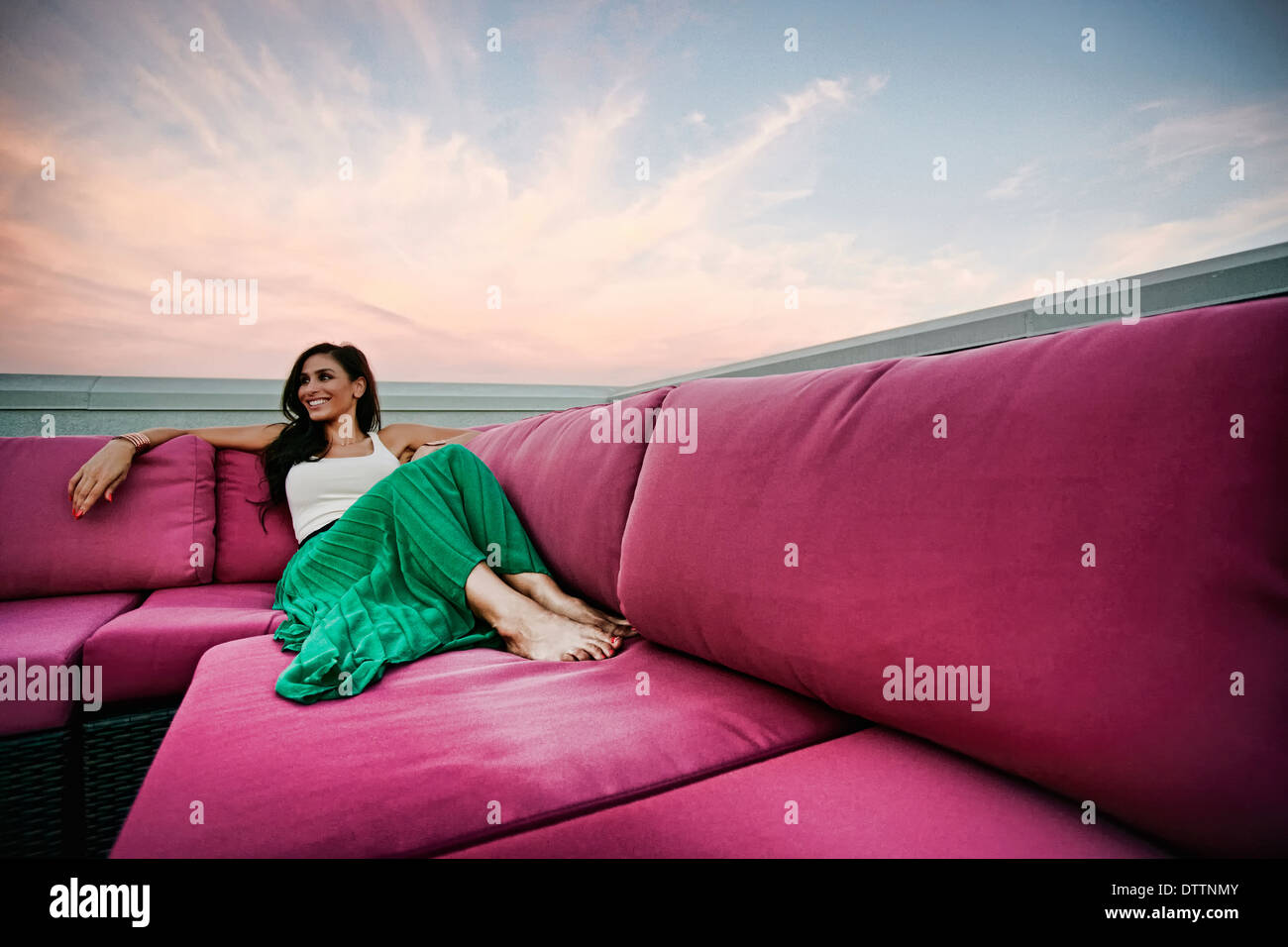 Middle Eastern woman relaxing on sofa outdoors Stock Photo