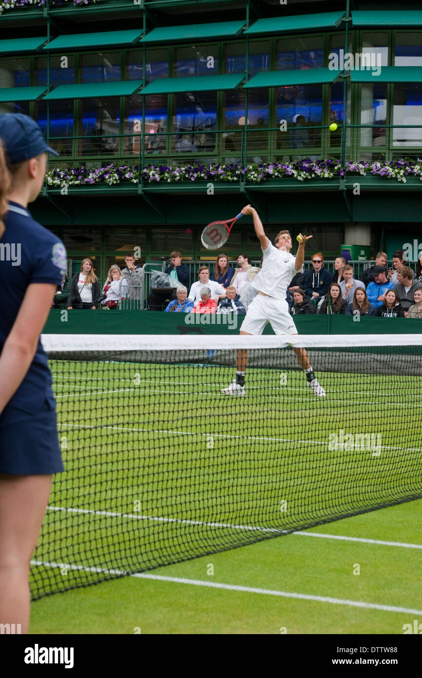Wimbledon Tennis championship player performs overhead smash with ball girl  and net in foreground crowd in background Stock Photo - Alamy