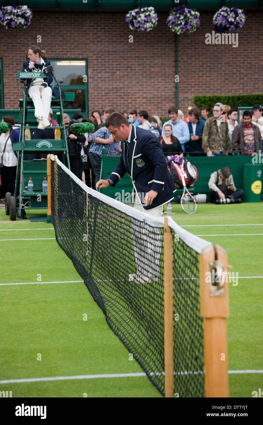 Wimbledon umpire in chair line court umpire checks net hight people watching Stock Photo