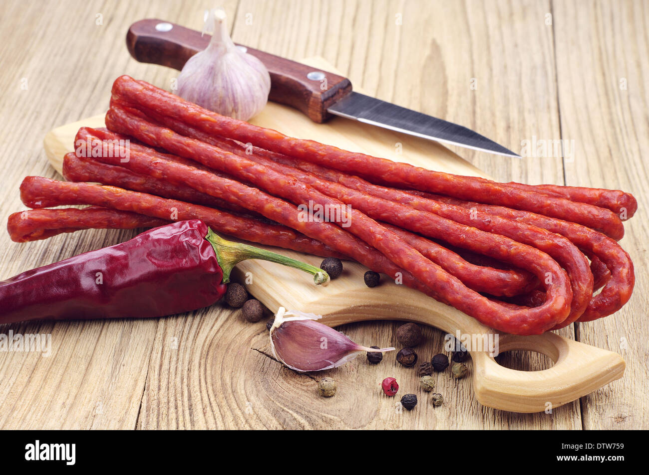 Long thin dry sausage, pepper and garlic on a cutting board Stock Photo