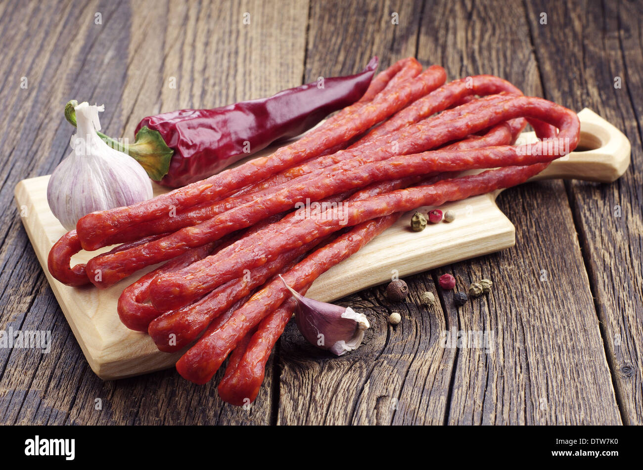 Long thin dry sausage, pepper and garlic on old wooden table Stock Photo