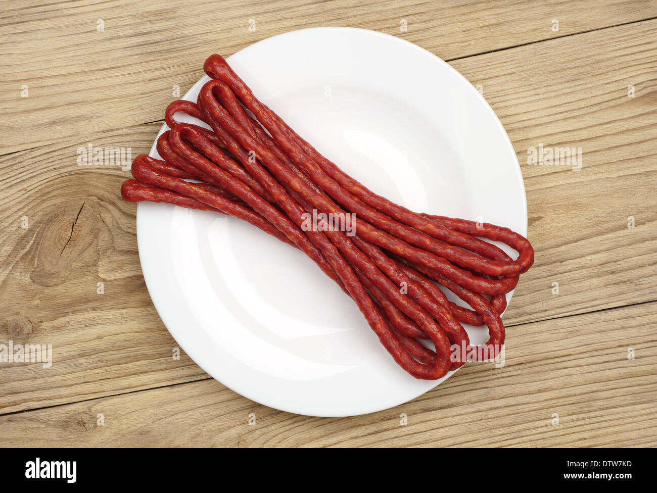 Thin dried sausages on white plate. Top view Stock Photo