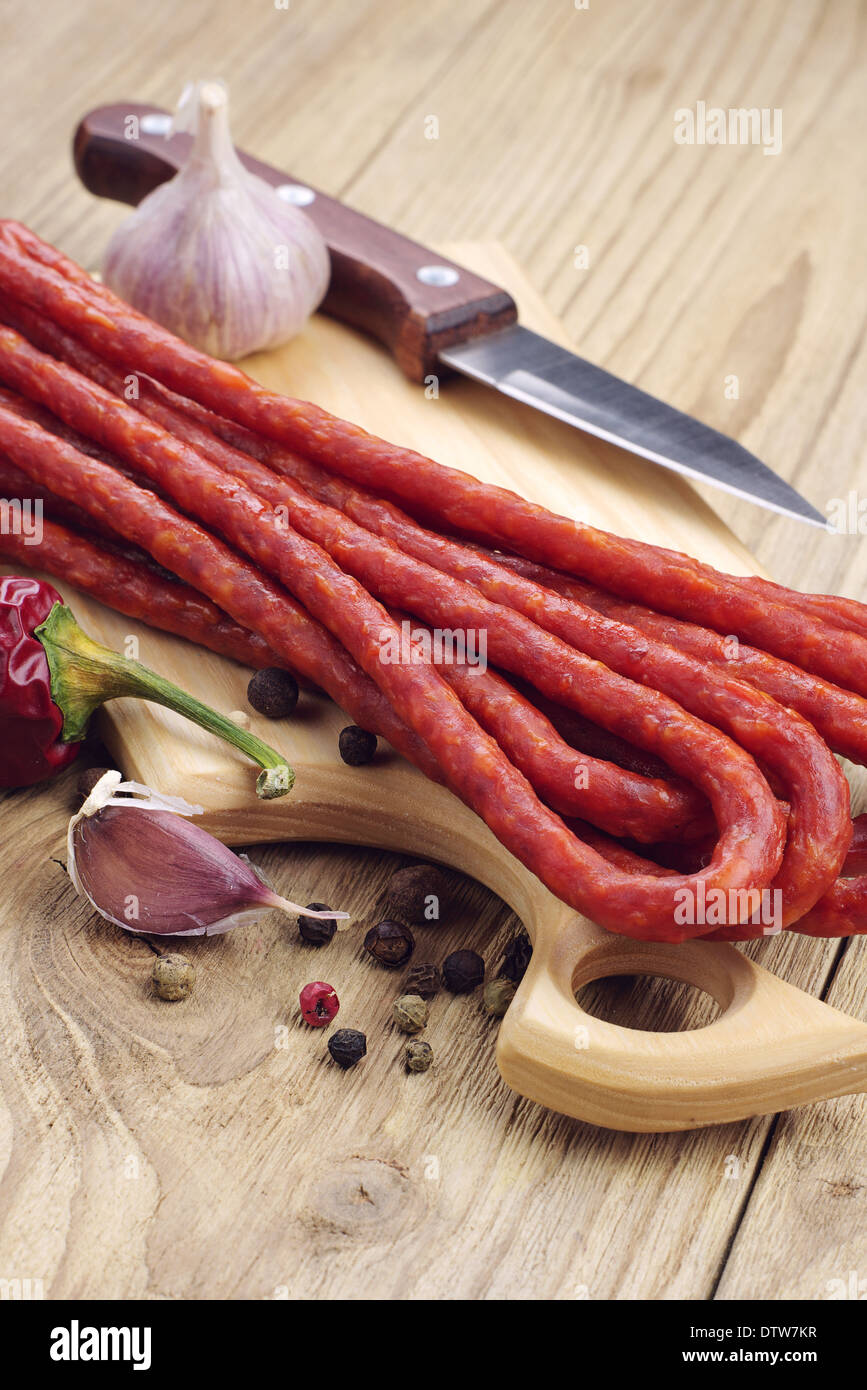 Thin dried sausages, pepper and garlic on a cutting board Stock Photo