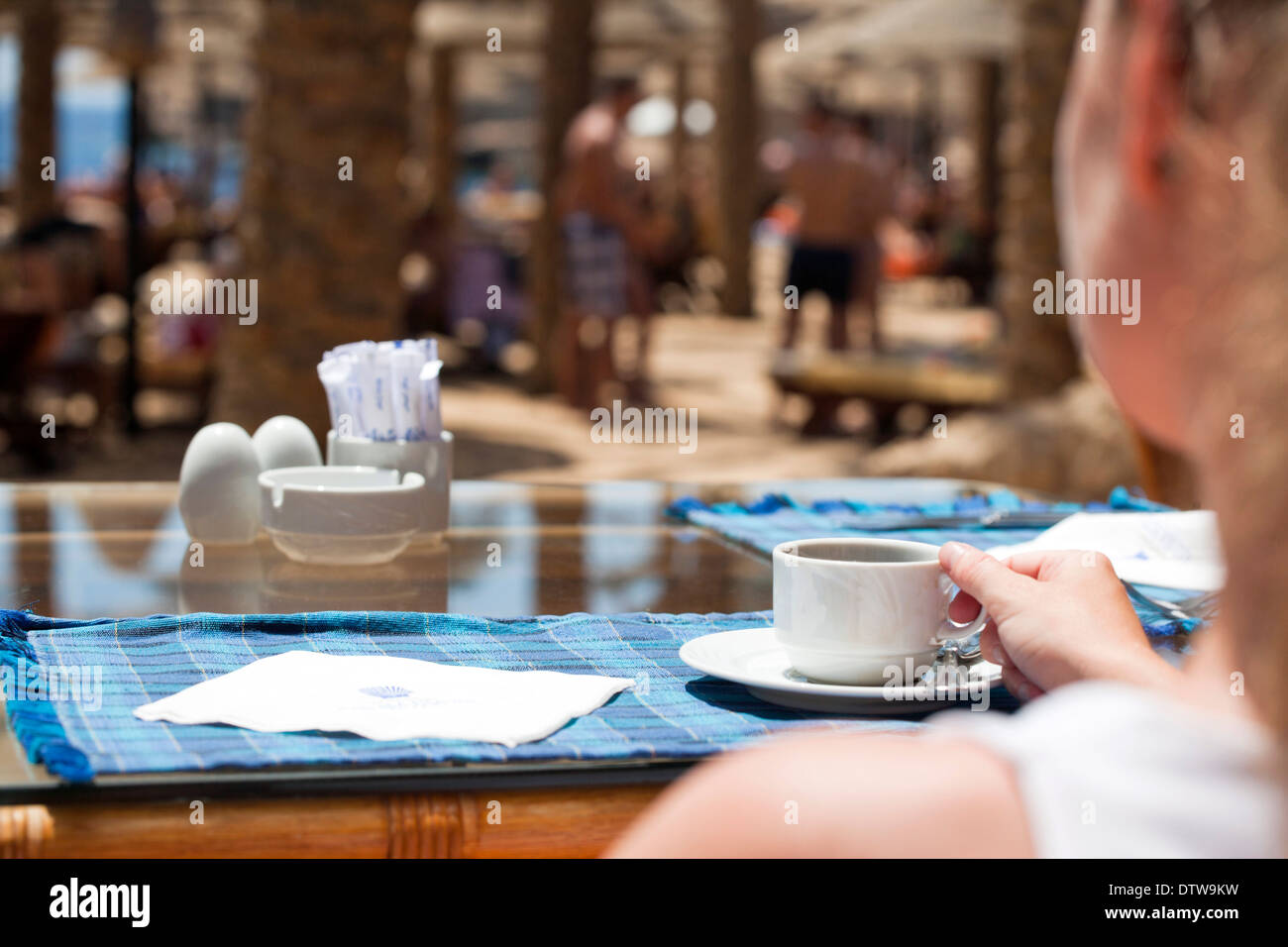 Abstract shallow focus image of a woman having coffee in a beach cafe Stock Photo