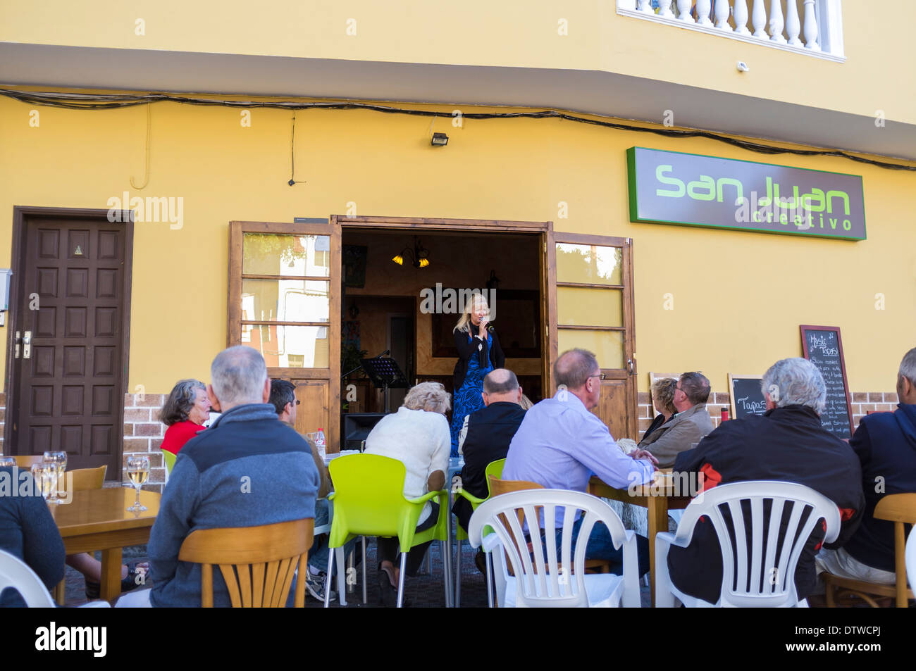 Blonde singer entertaining customers at a restaurant in Playa San Juan, canary Islands, Spain. Stock Photo
