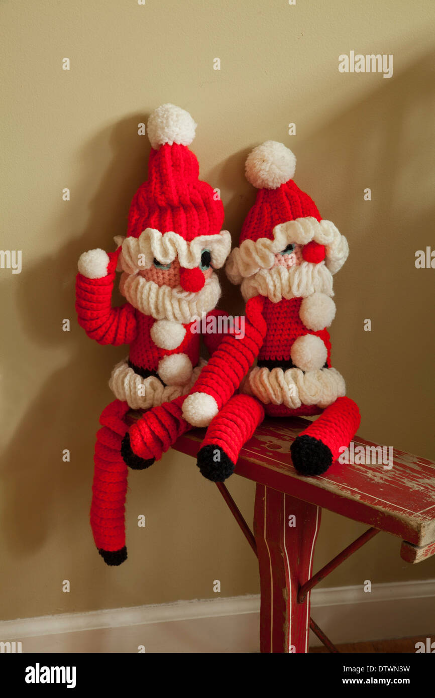 Two jolly crocheted Santas sit together on an old jumper (a kind of sled with one runner). Stock Photo