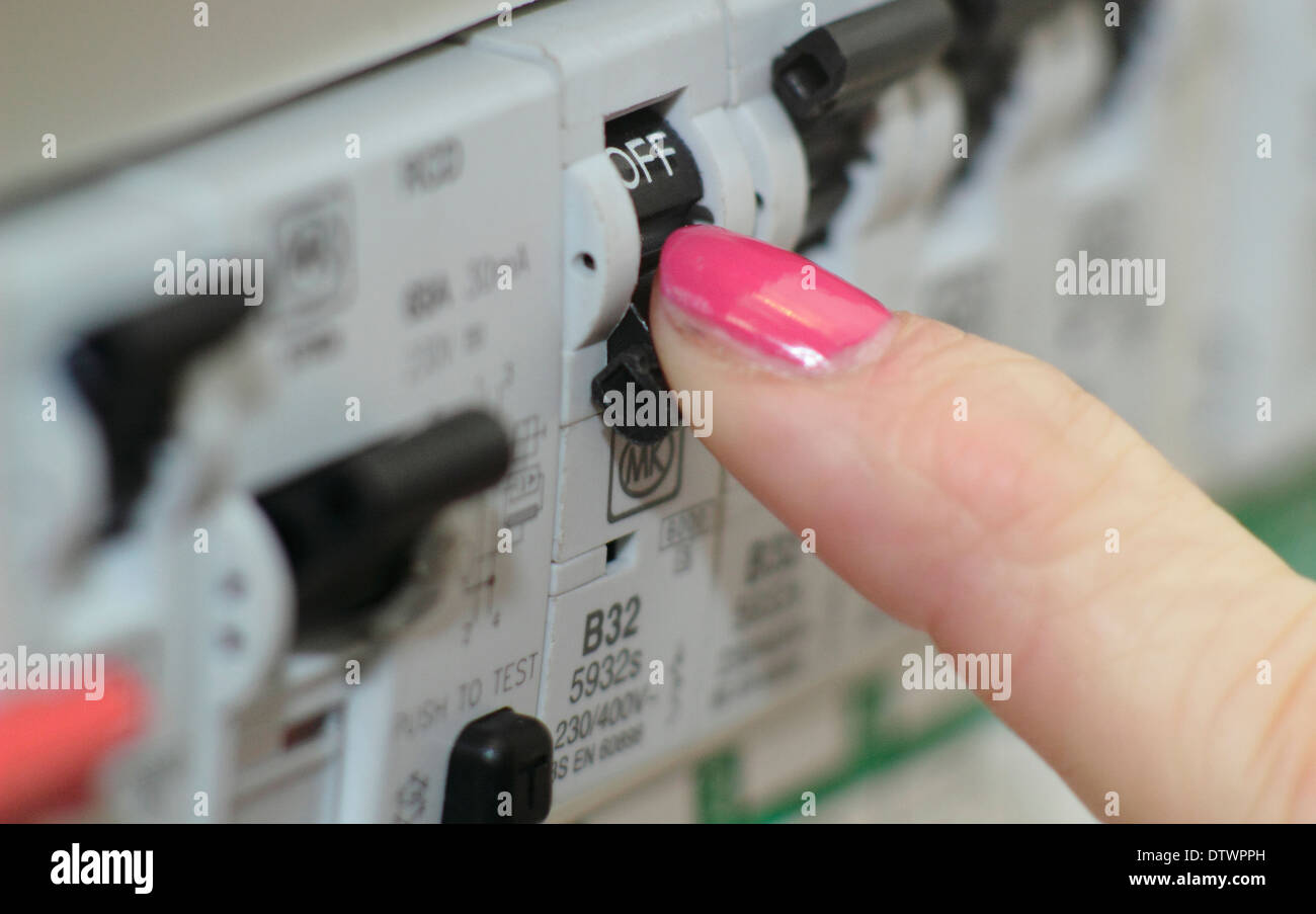 Woman switches trip/residual current device (RCD) / consumer unit in a domestic setting/home