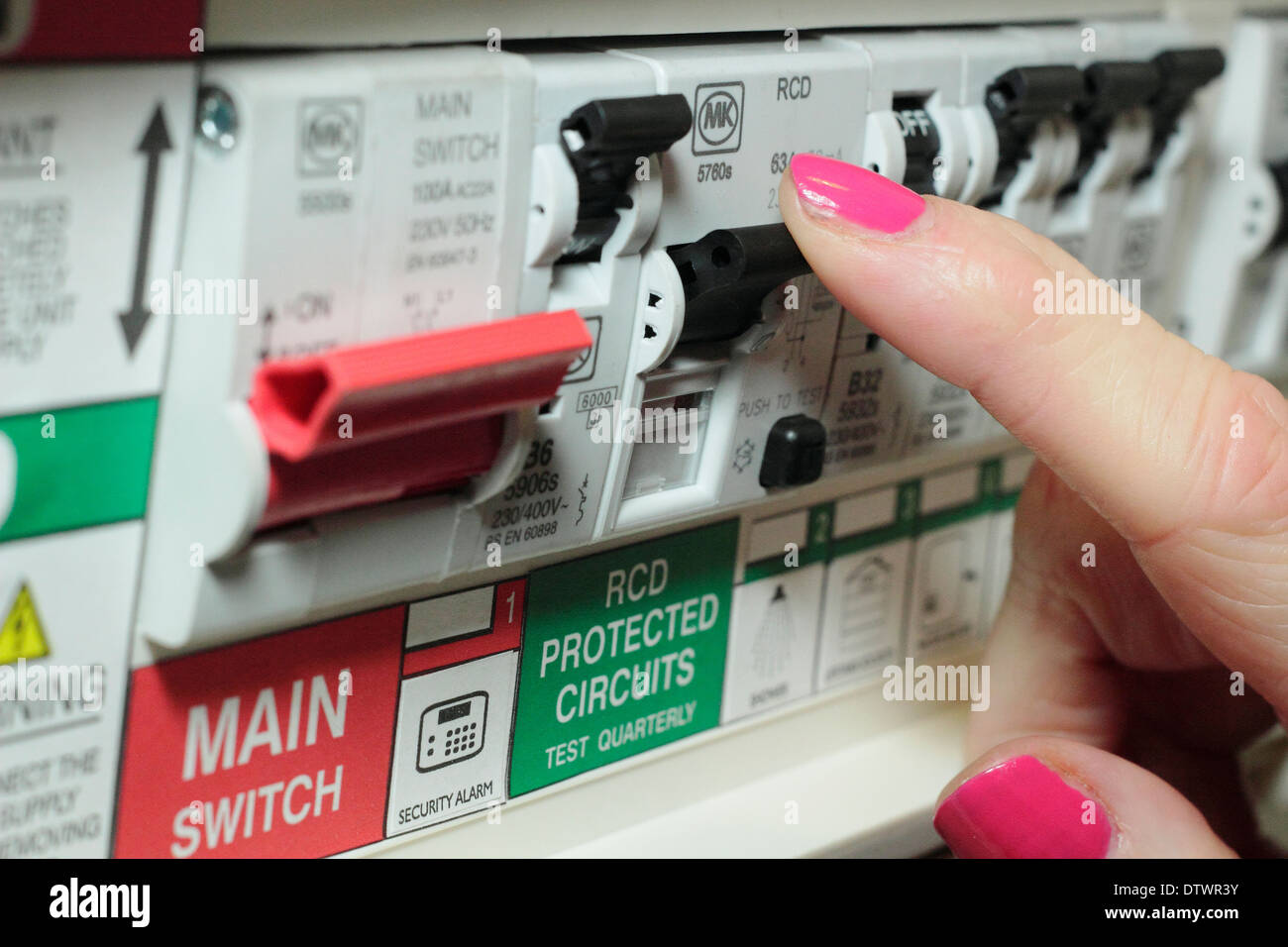 Woman switches trip/residual current device (RCD) / consumer unit in a domestic setting/home