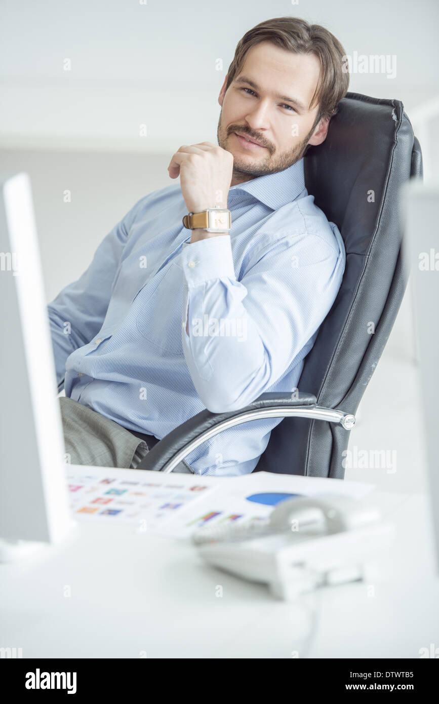 Handsome businessman sitting in chair in front of computer Stock Photo ...