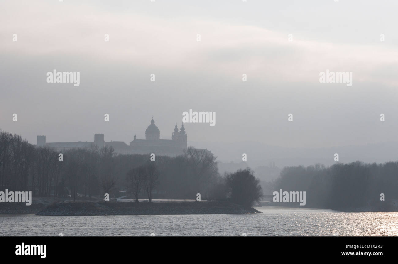 Melk Abbey monastery in the fog. Atop a high cliff the massive abbey appears out of the mist above the broad Danube River. Stock Photo