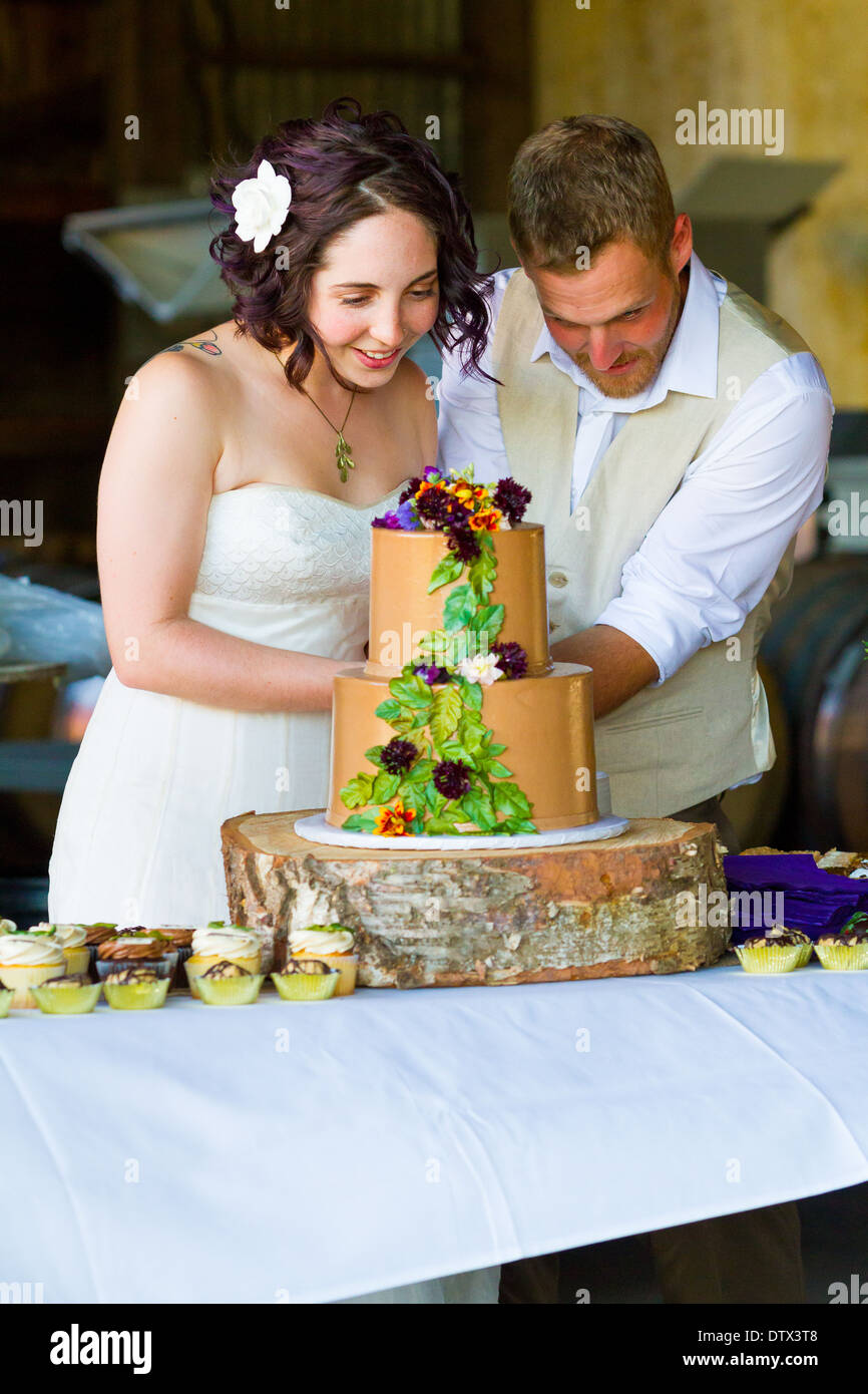 Bride and groom cut their wedding cake at a reception with a tree theme. Stock Photo