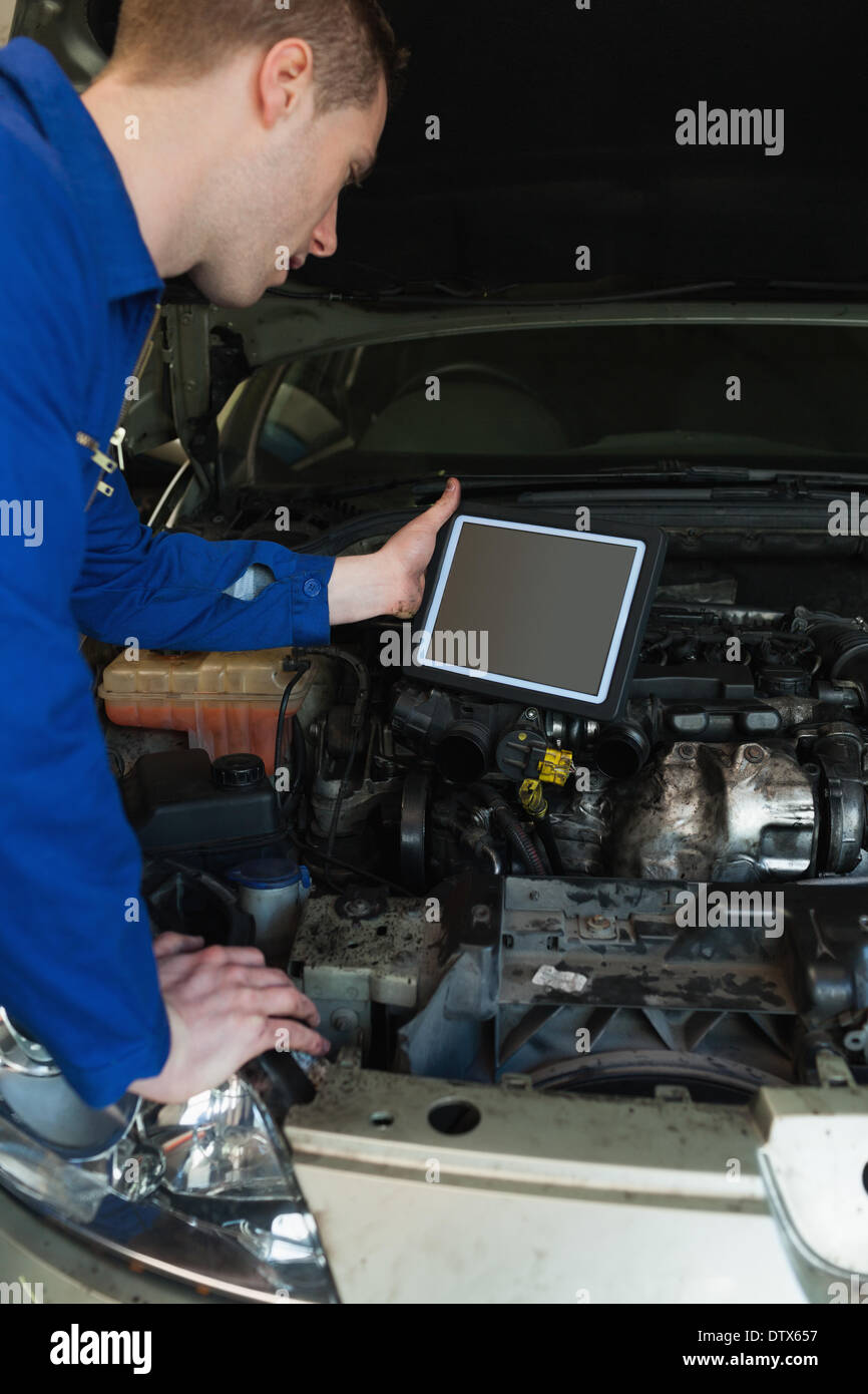 Mechanic by car holding tablet pc Stock Photo