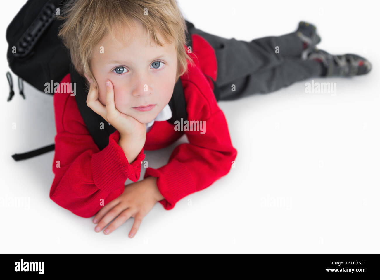 Boy lying on floor with schoolbag Stock Photo