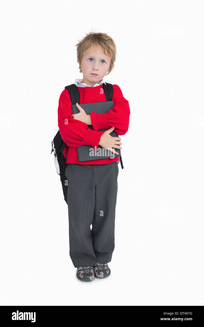 Young boy with schoolbag and book standing Stock Photo