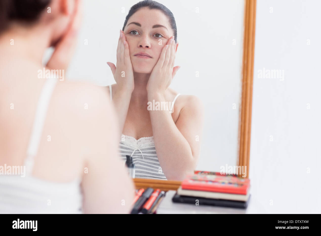 Неприятный небольшой. Массаж лица перед зеркалом. Женщина в зеркале массаж. Девушка у зеркала массаж. Женщина у зеркала делает массаж лица.